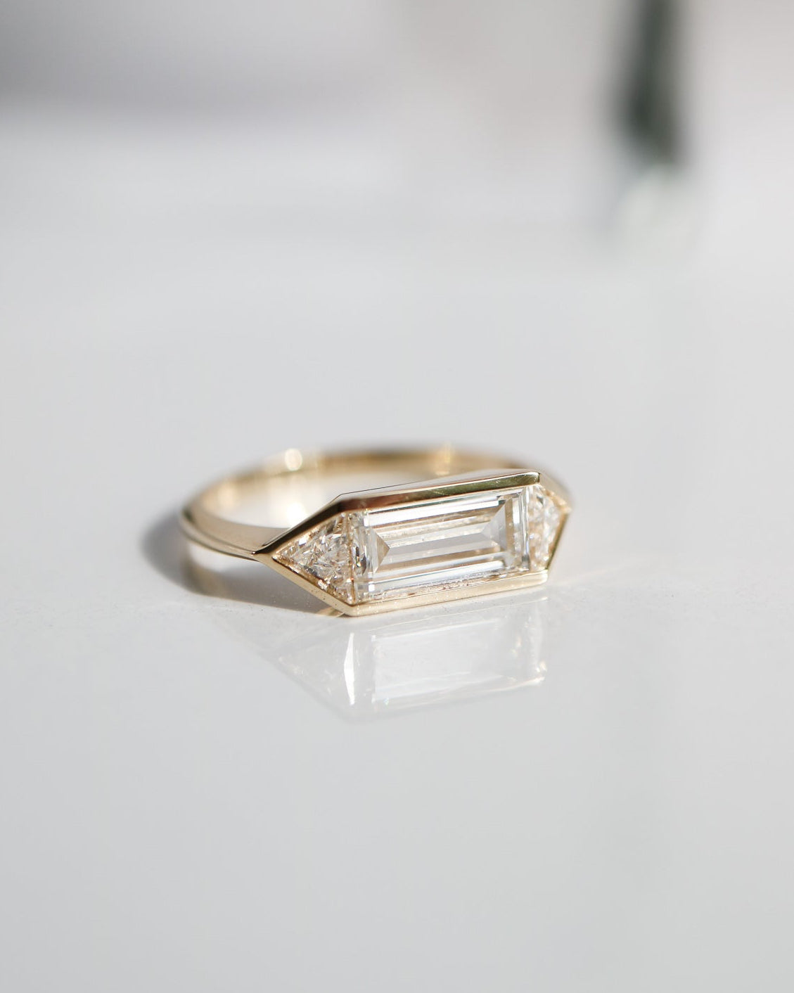 Gold ring with diamonds on a light gray background