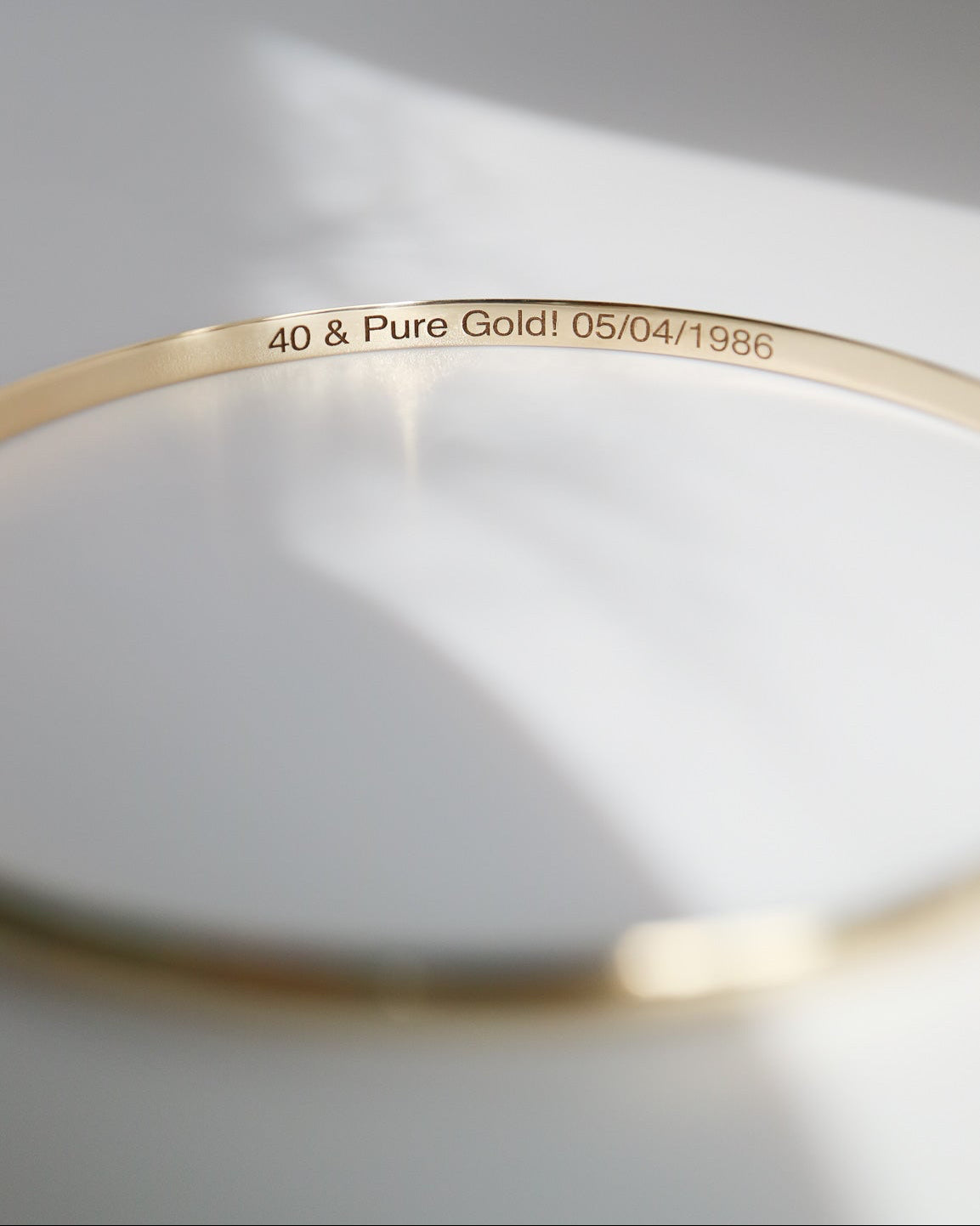 Gold bracelet with engraved text on a light gray background