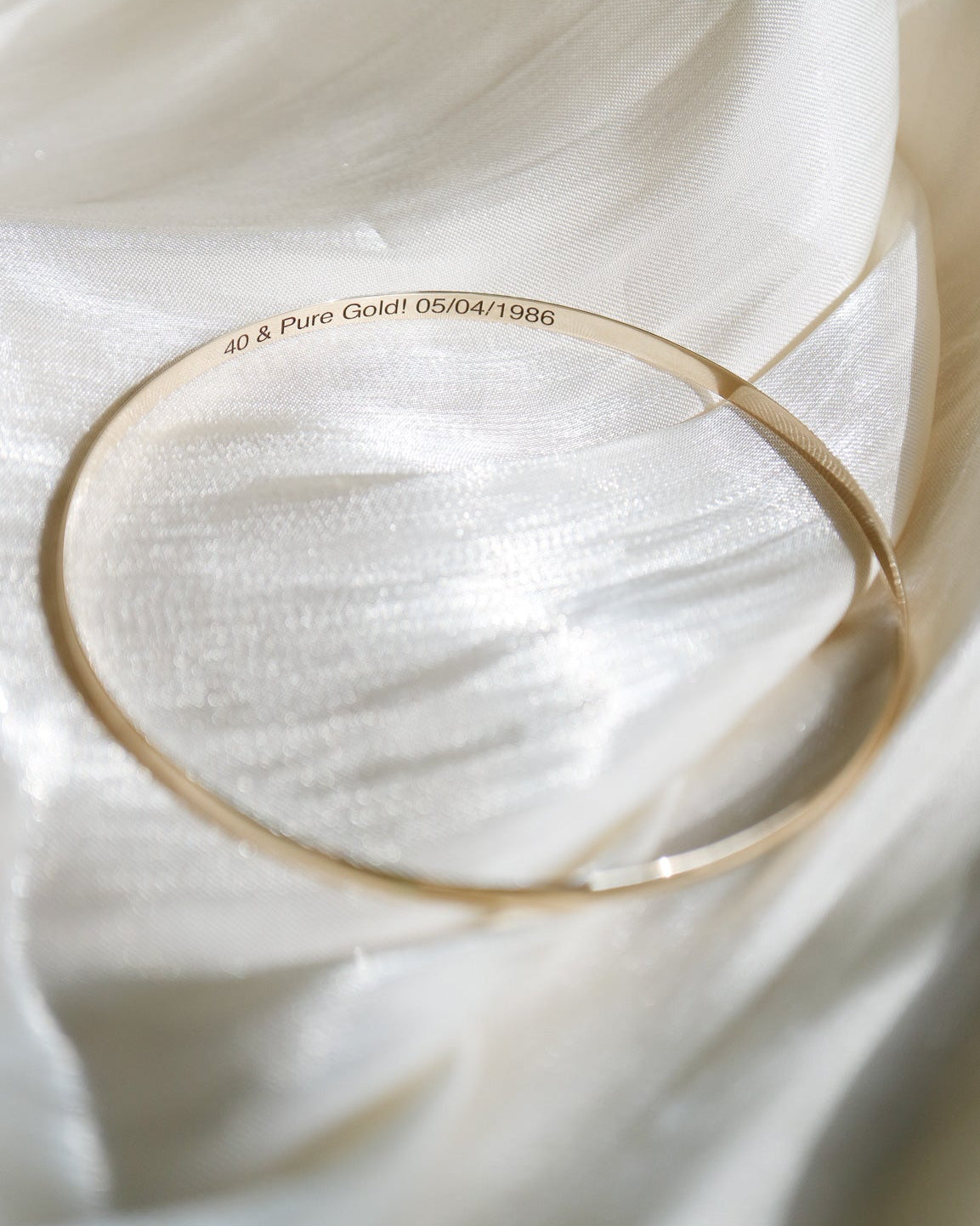 Gold bangle on a white fabric background