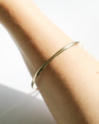 Gold bracelet on a person's wrist with a light background