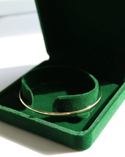Gold ring in a green jewelry box on a white surface