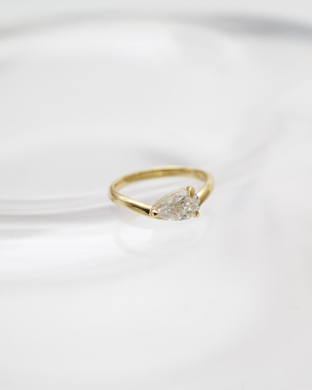 Gold ring with a diamond on a white fabric background