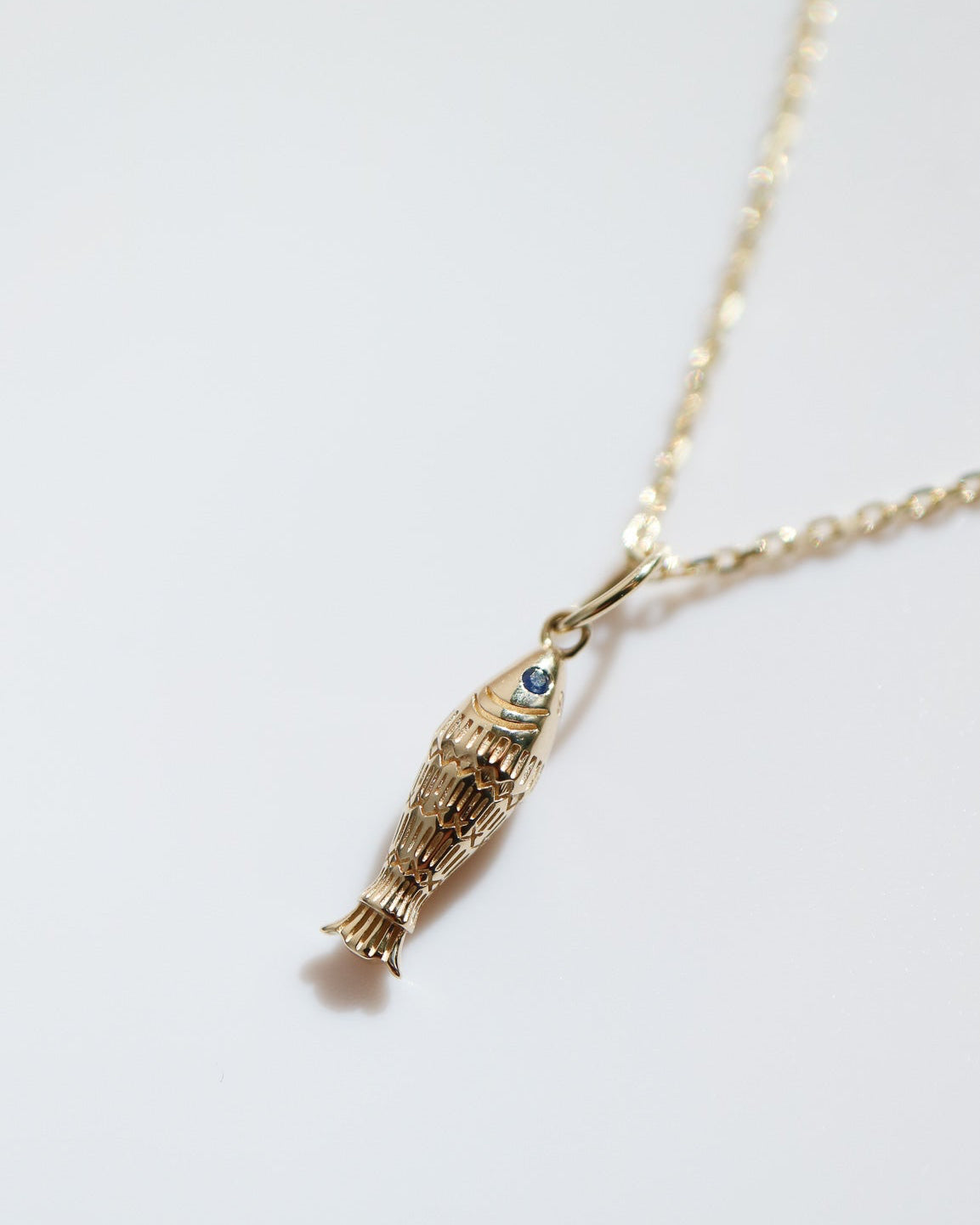 Gold fish-shaped pendant necklace on a white background