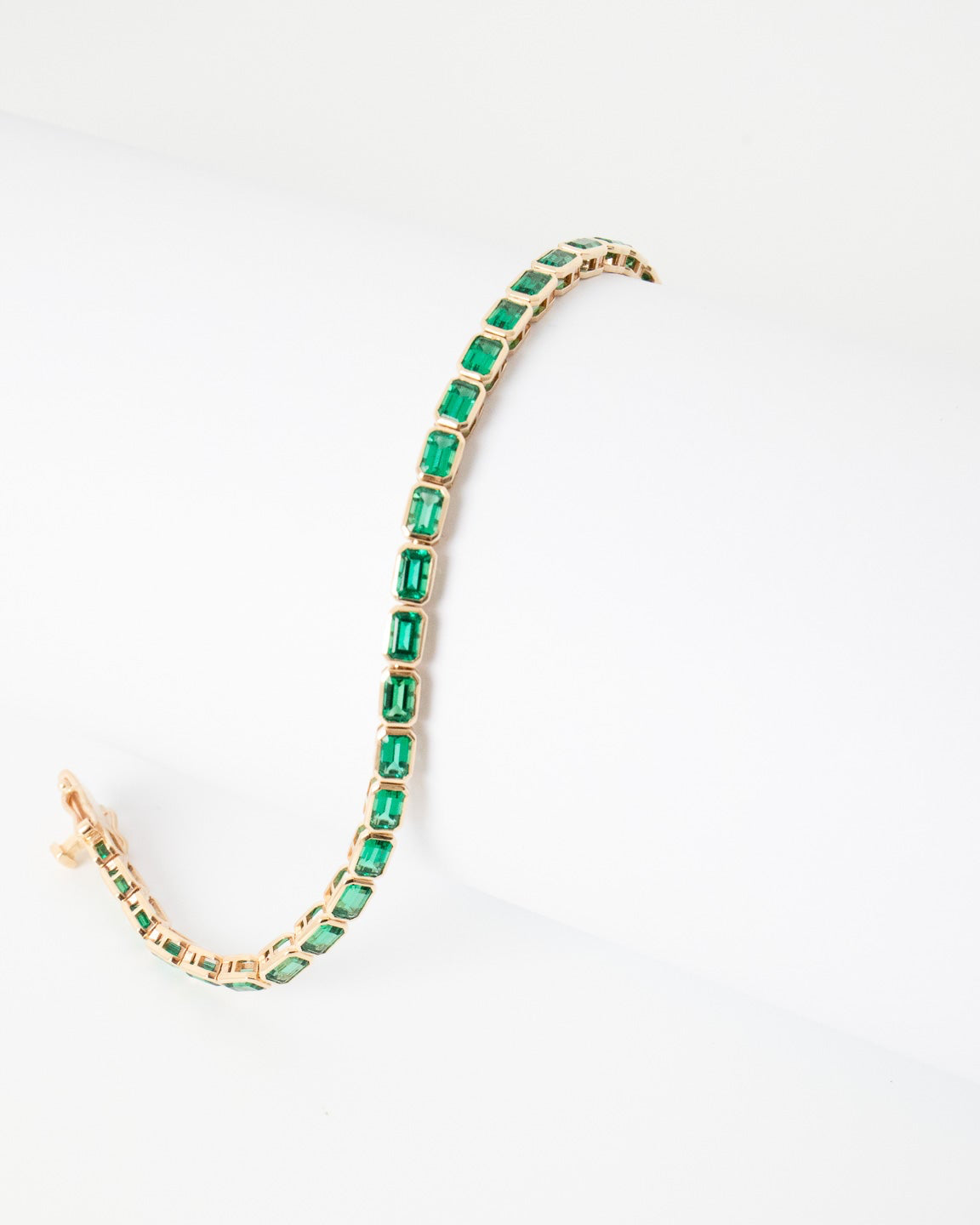 Gold necklace with green gemstones on a white background