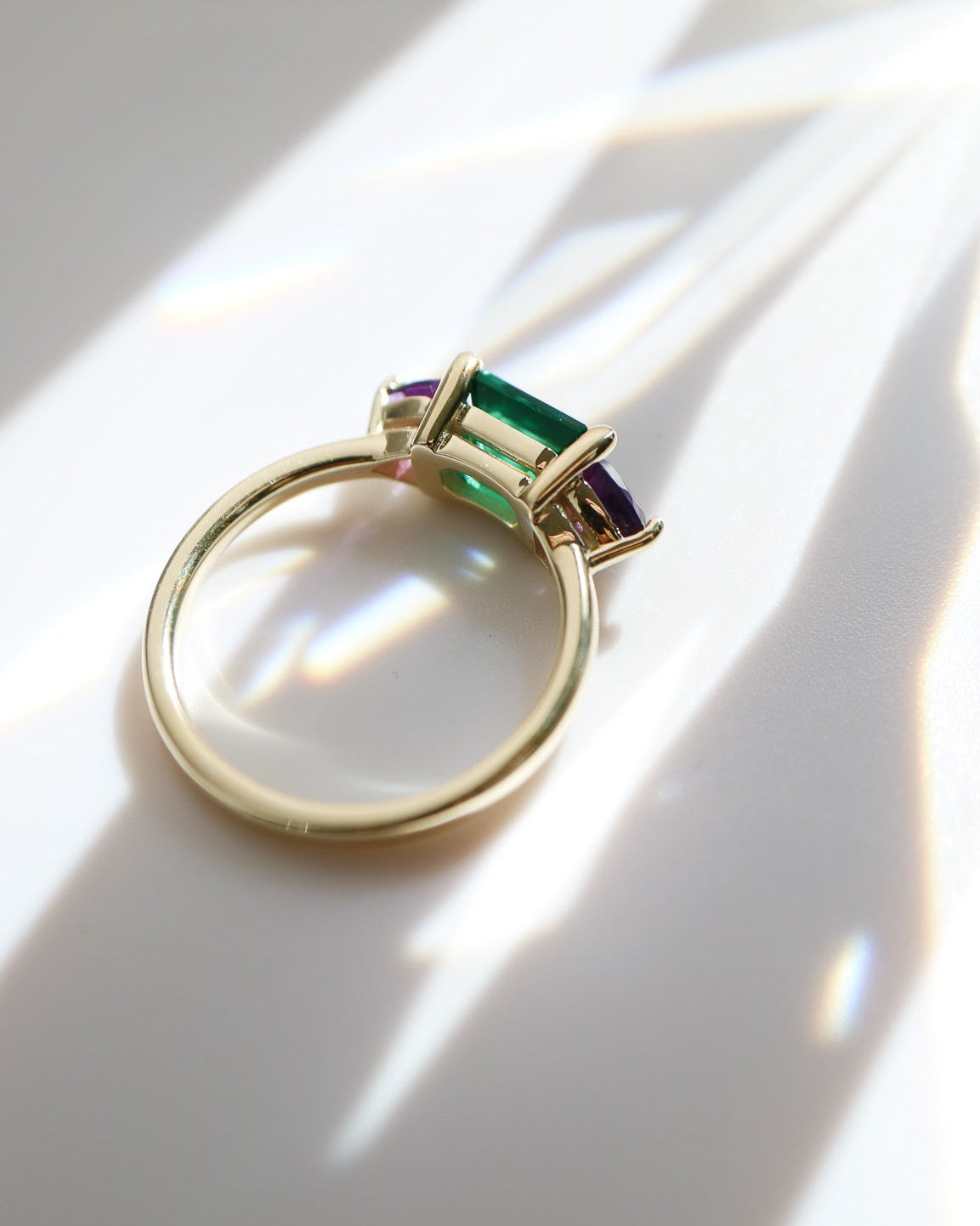 Gold ring with green gemstone on a white surface