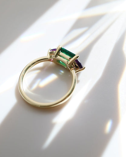Gold ring with green gemstone on a white surface