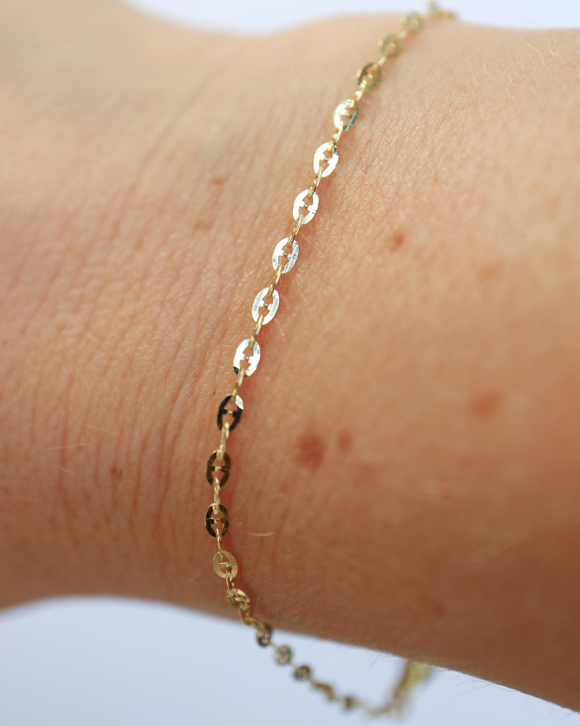 9ct solid gold Mini Gucci Link Chain bracelet on a a female wrist, showcasing its delicate interlocking links and polished gold finish.