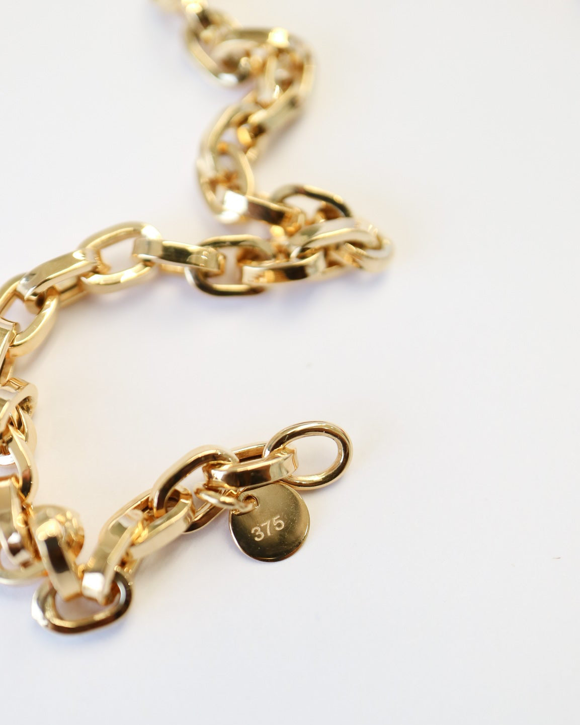 9kt solid gold Paperclip Cable Bracelet close up featuring polished elongated links and a modern gold chain design and disc stamped with the 375 gold weight