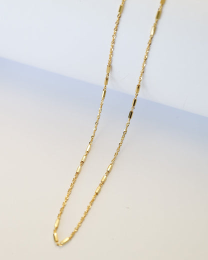 9kt solid gold Morse Code Chain necklace featuring a delicate gold chain with polished rectangular bar accents, photographed on an off-white background.