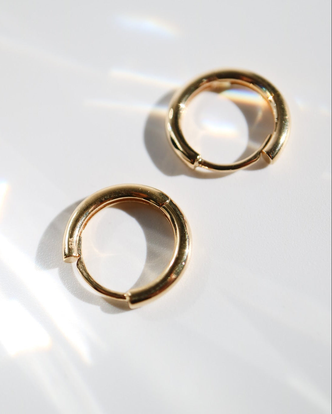 Pair of 9kt solid gold Rounded Huggie Earrings with a polished finish and classic circular design, shown worn on a white background