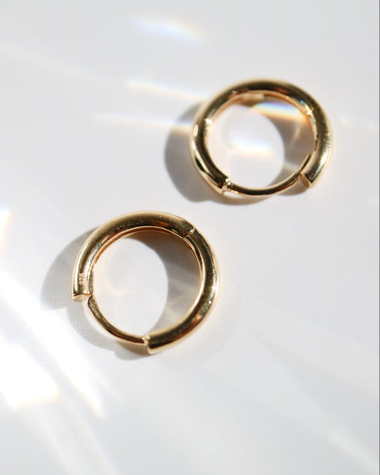 Pair of 9kt solid gold Rounded Huggie Earrings with a polished finish and classic circular design, shown worn on a white background