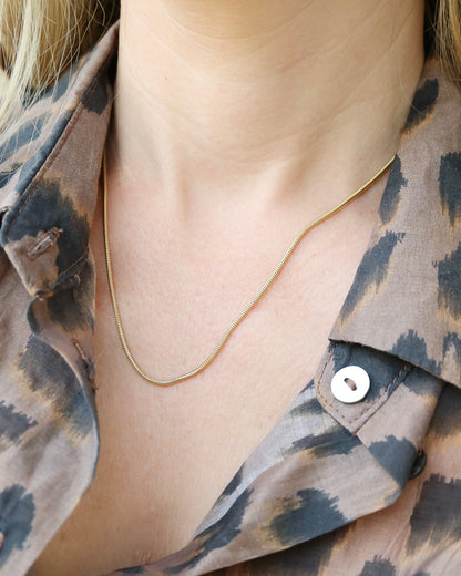 9ct gold Skinny Real Snake Chain on female wearing sheer leopard print shirt
