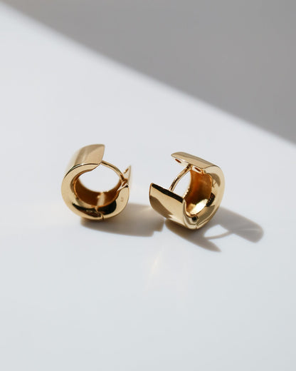Pair of polished 9ct yellow gold Arc Huggie earrings with a sculptural curved design and secure hinged fastening.