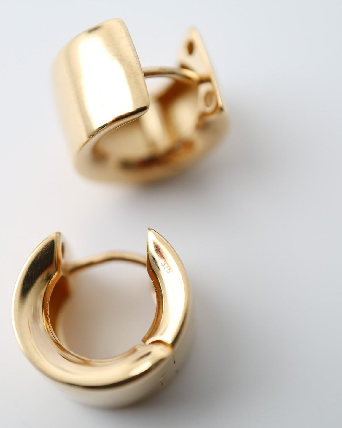 Gold hoop earrings on a light gray background
