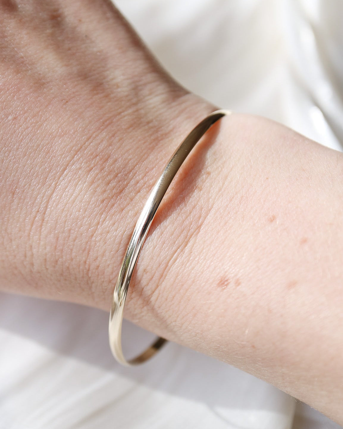 Gold bracelet on a wrist with a white background