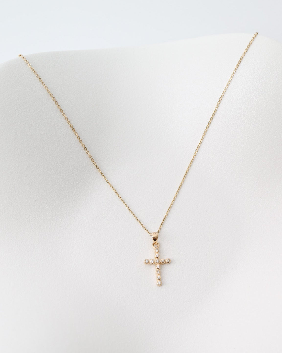 Gold cross necklace on a white dish