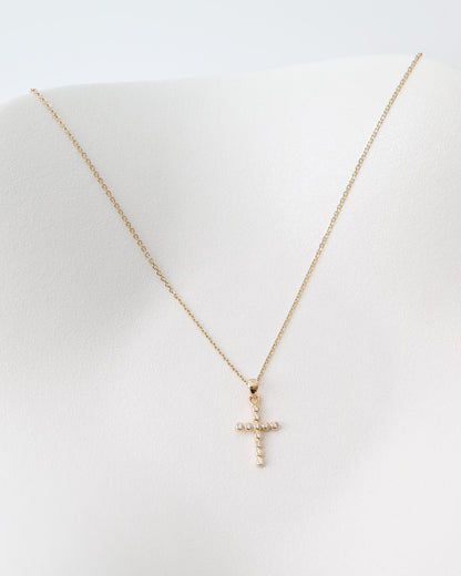 Gold cross necklace on a white dish