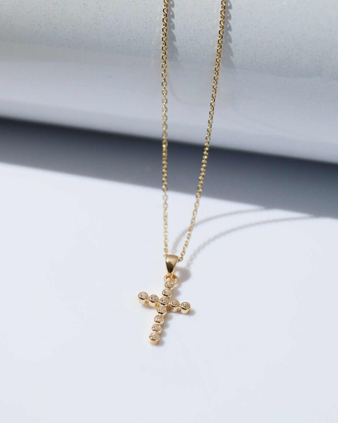 Gold cross necklace on a white background