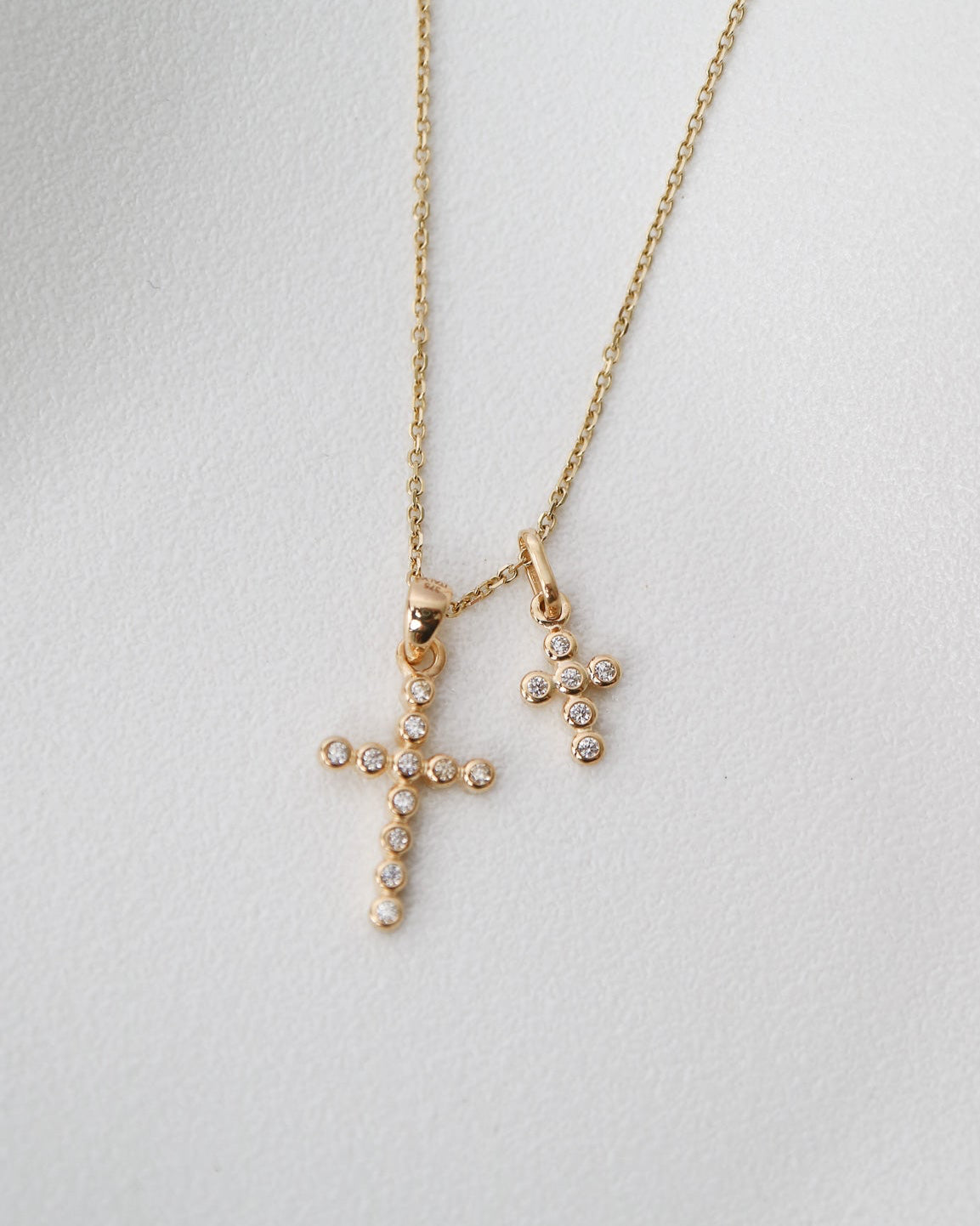Gold necklace with cross pendants on a light gray background