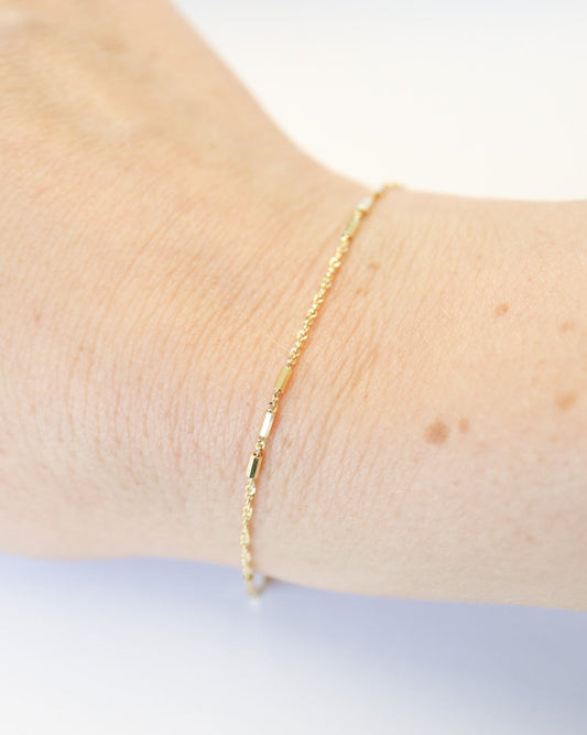 9kt solid gold Morse Code Chain bracelet featuring a delicate gold chain with polished rectangular bar accents, photographed on a female wrist