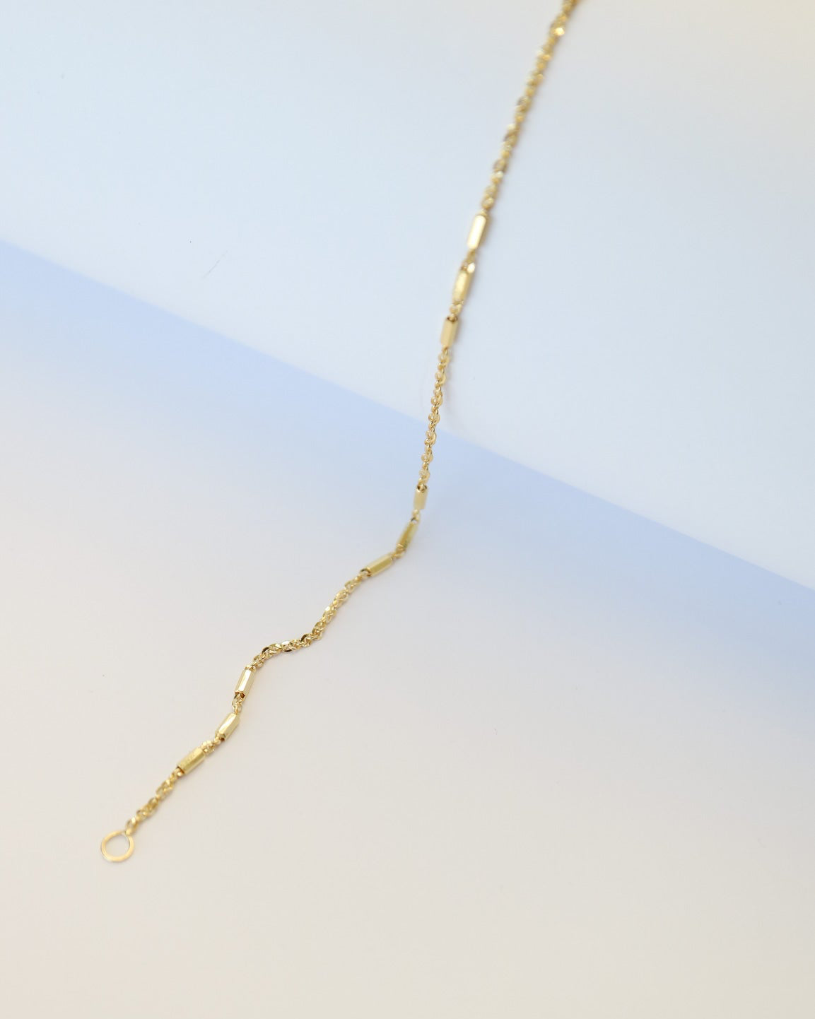 9kt solid gold Morse Code Chain bracelet featuring a delicate gold chain with polished rectangular bar accents, photographed on an off-white background.