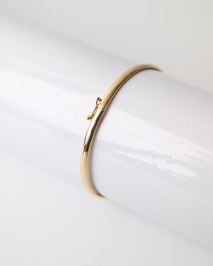 9kt solid gold Classic Oval Bangle with a polished finish, lightweight hollow construction and flexible design, photographed on a white background.