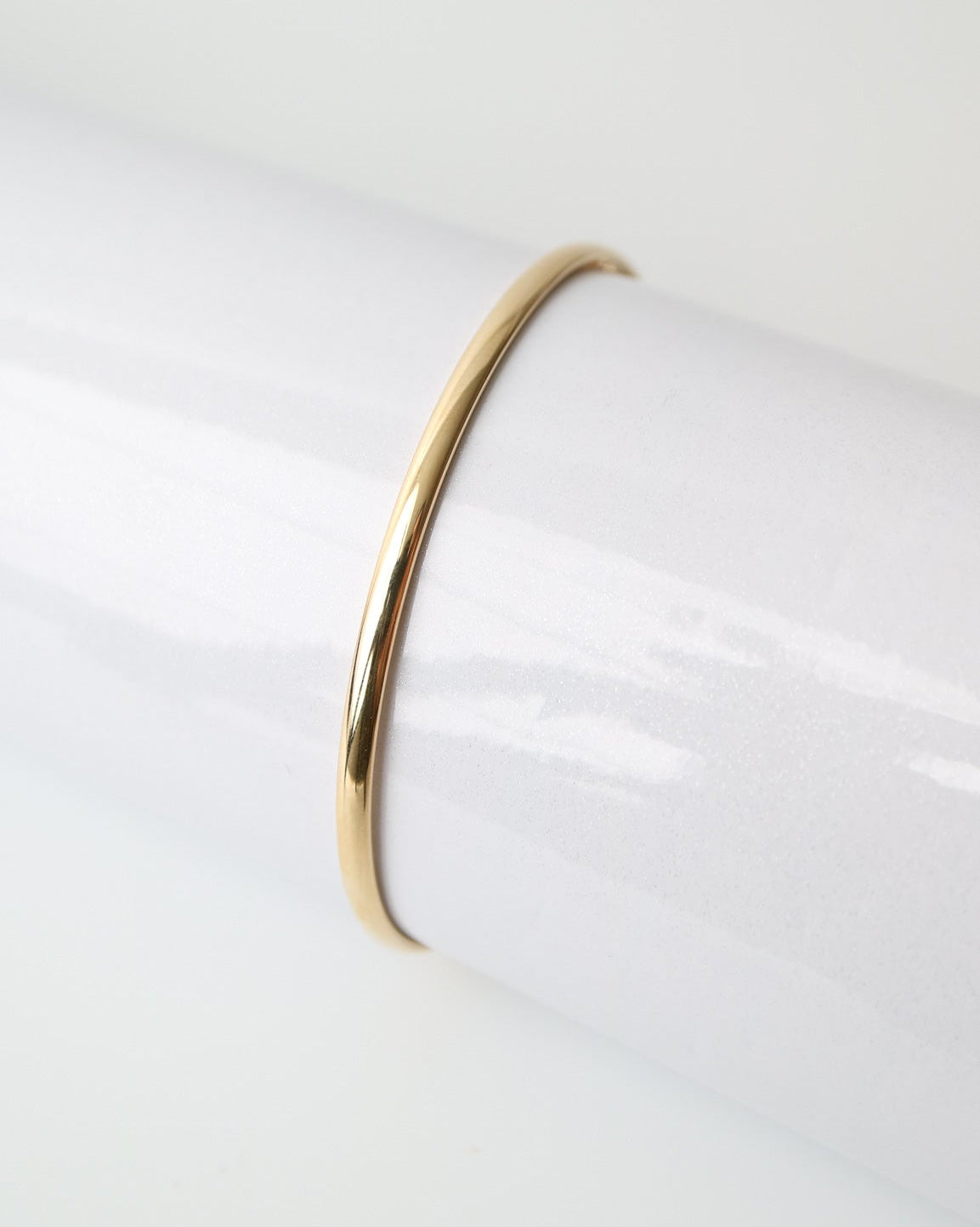 9kt solid gold Classic Oval Bangle with a polished finish, lightweight hollow construction and flexible design, photographed on a white background.