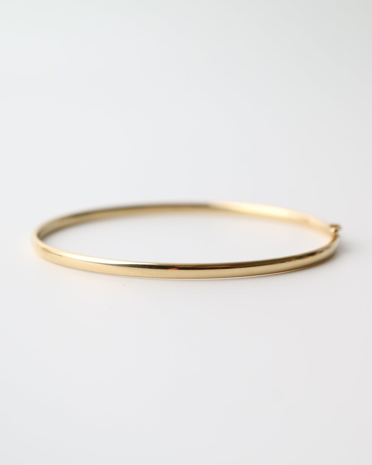 9kt solid gold Classic Oval Bangle with a polished finish, lightweight hollow construction and flexible design, photographed on a white background.
