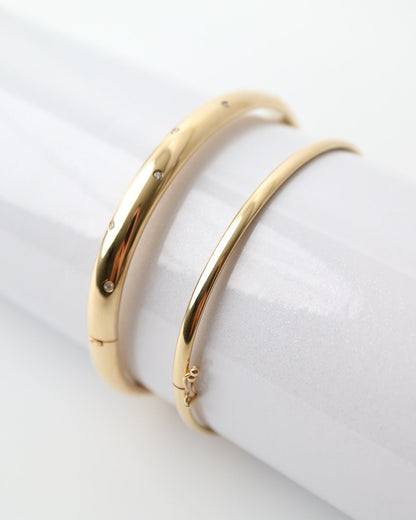 9kt solid gold Classic Oval Bangle with a polished finish, lightweight hollow construction and flexible design, photographed on a white background stacked with a wider 9ct gold bangle