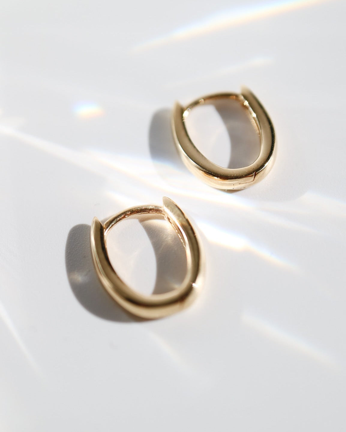 9kt solid gold Rounded V-Shaped Huggie Earrings featuring a polished finish, rounded silhouette and subtle V-shaped base, photographed on white