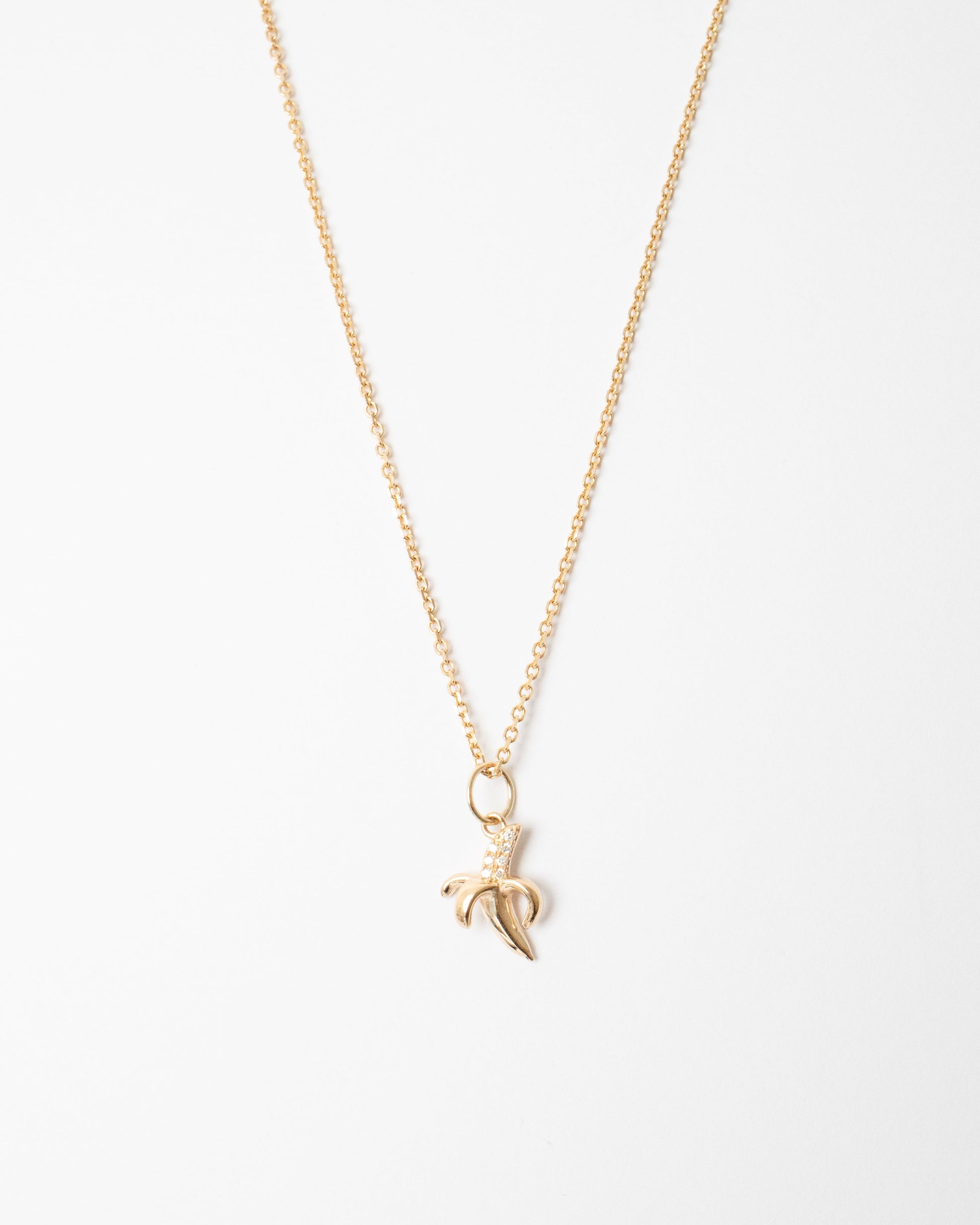 Gold necklace with a banana leaf pendant on a white background