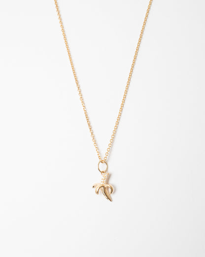 Gold necklace with a banana leaf pendant on a white background