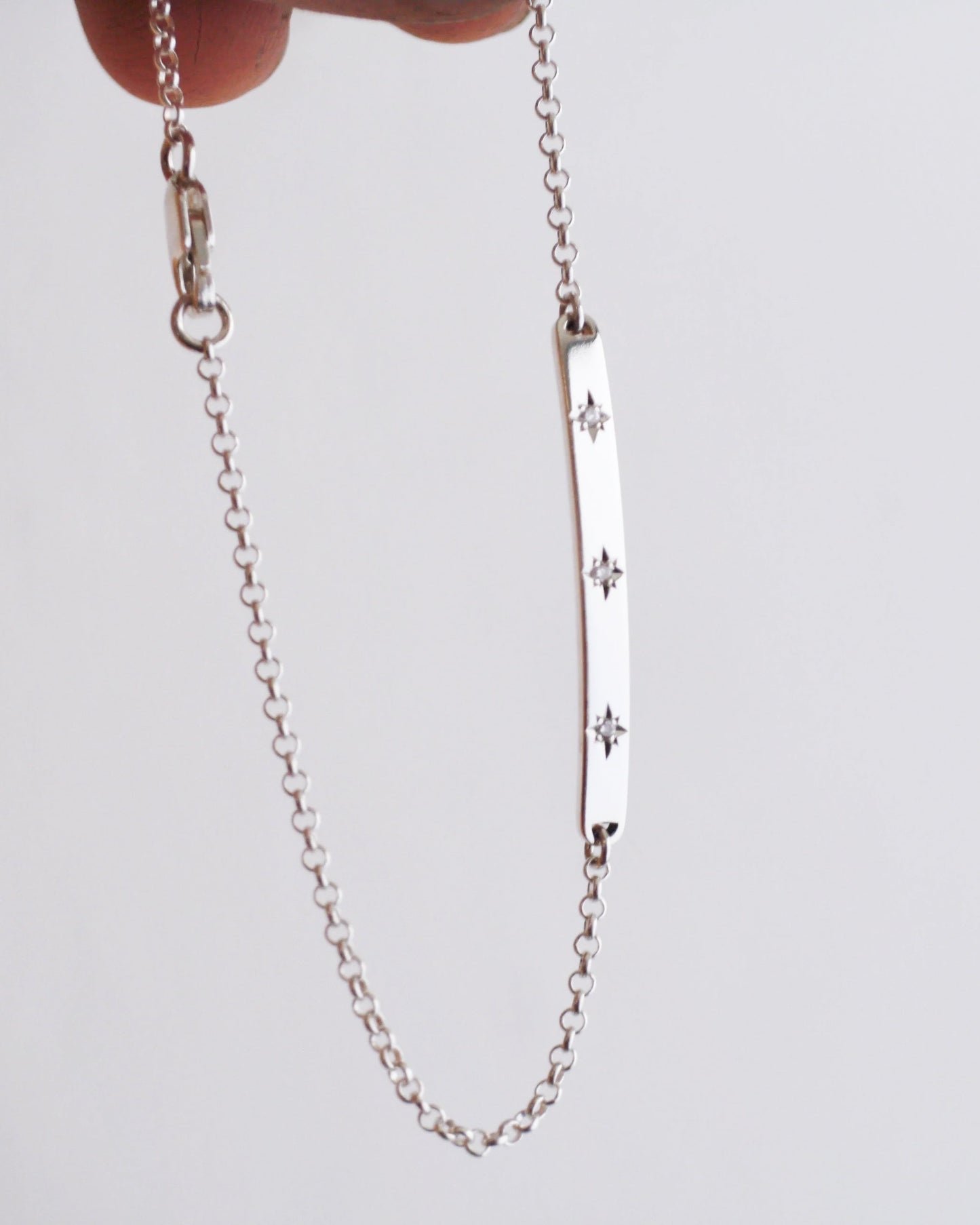 Silver chain bracelet with star designs on a light gray background