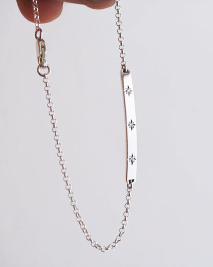 Silver chain bracelet with star designs on a light gray background