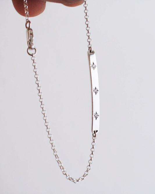 Silver chain bracelet with star designs on a light gray background