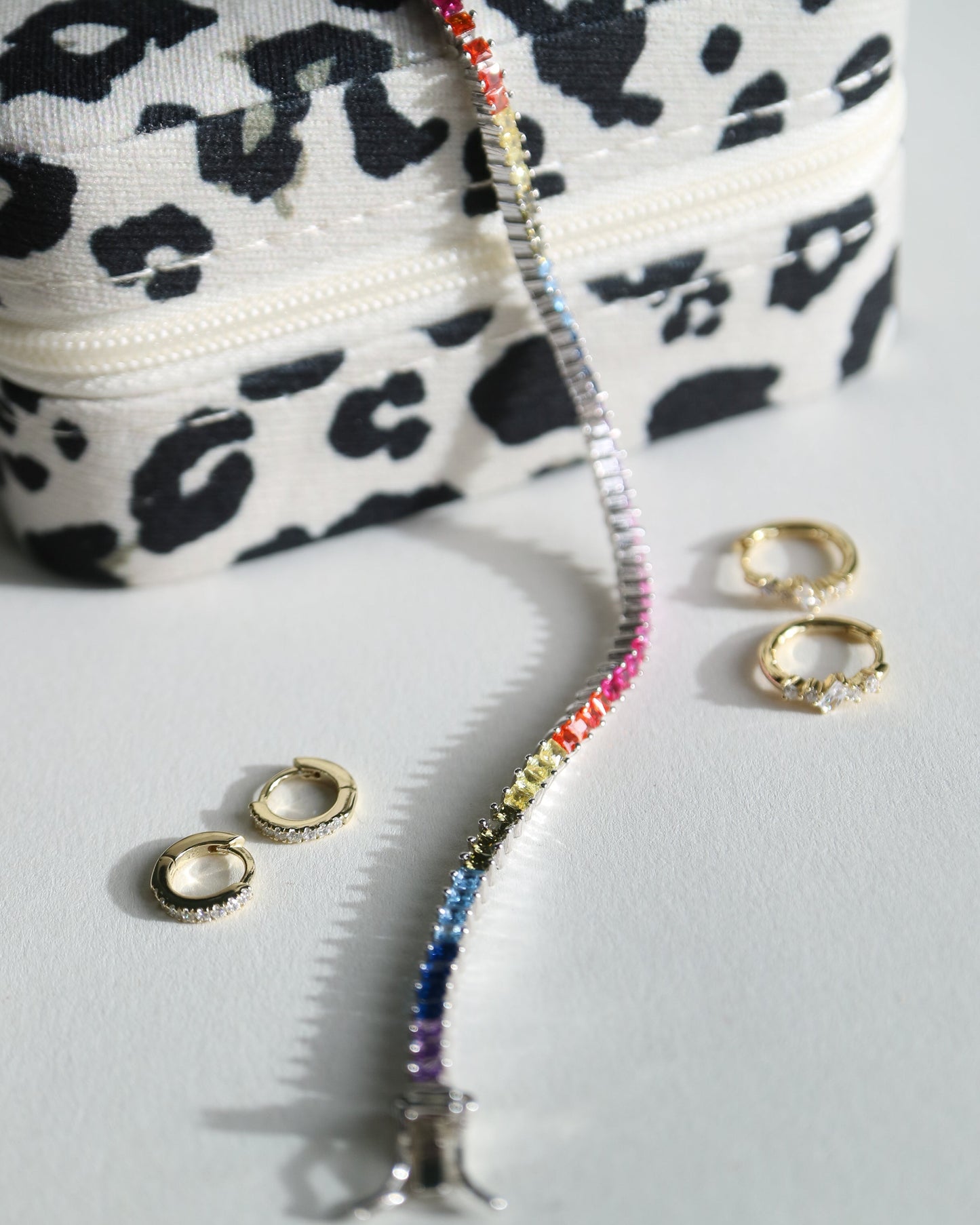 Leopard print makeup bag with colorful zipper and gold rings on a light gray background