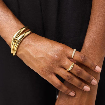 Hand wearing a gold bracelet and ring on a black background