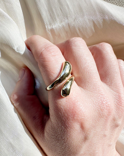 Gold ring on a person's finger with a soft white fabric background