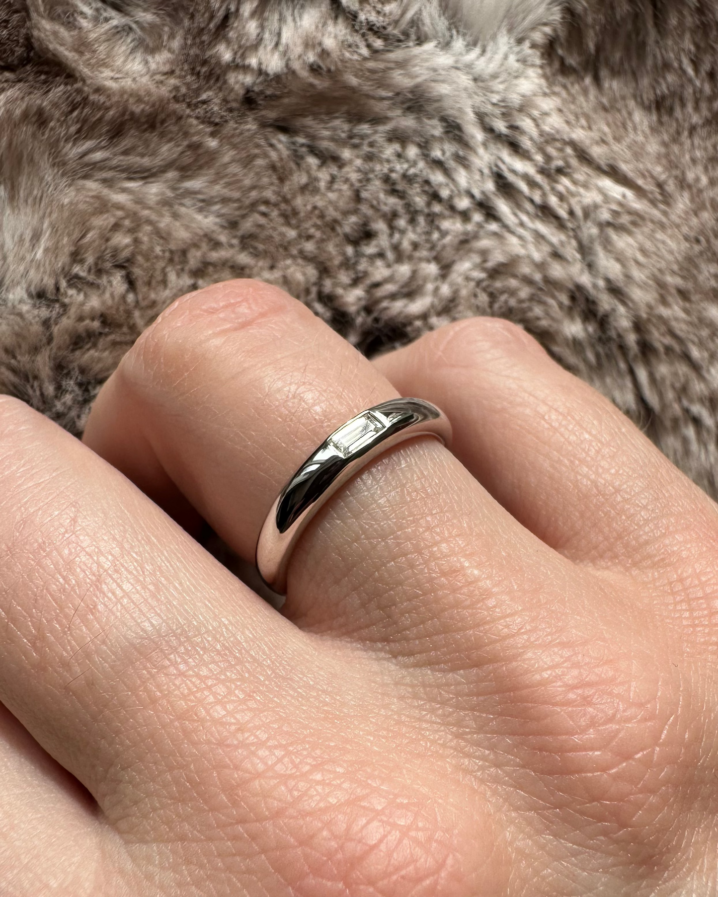 Silver ring on a person's finger with a soft fur background