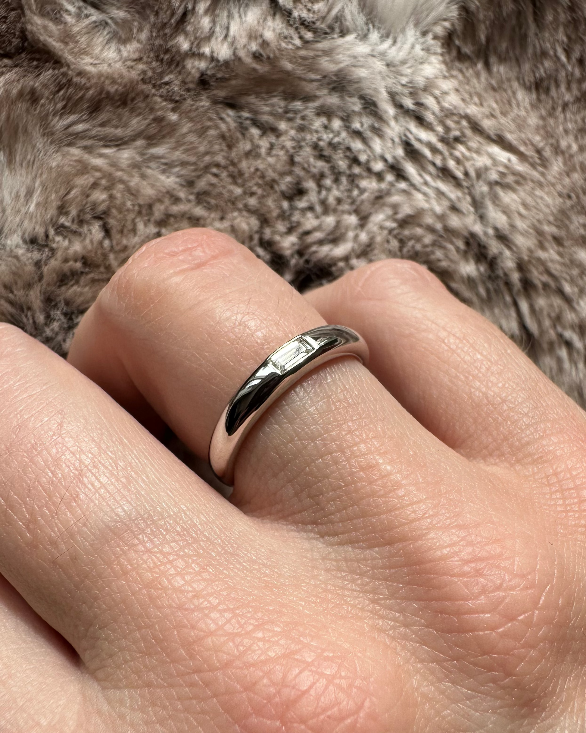Silver ring on a person's finger with a soft fur background