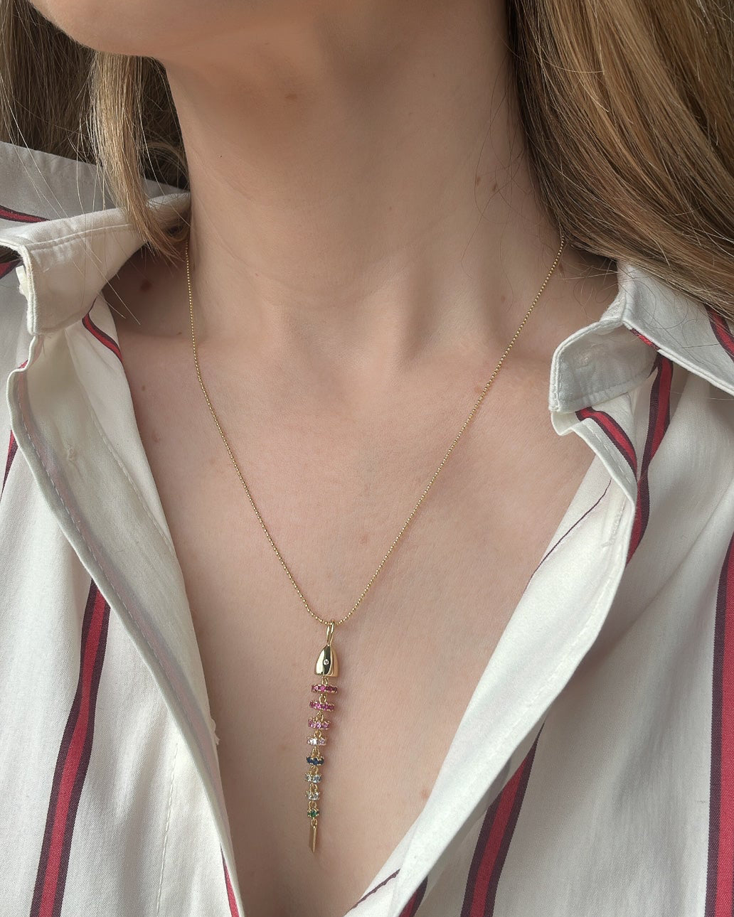 Close-up of a person wearing a delicate necklace with small pendants.