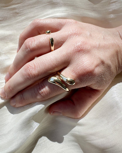 Close-up of a hand wearing two gold rings on a light background