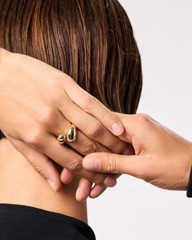 Person wearing gold jewelry with a plain background