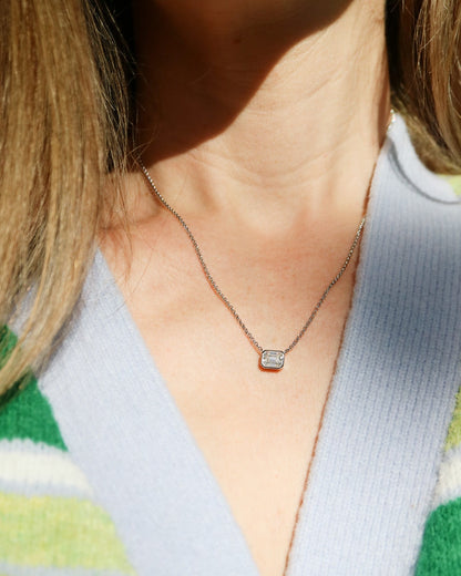 Necklace with a small pendant worn by a person in a green and white striped sweater.