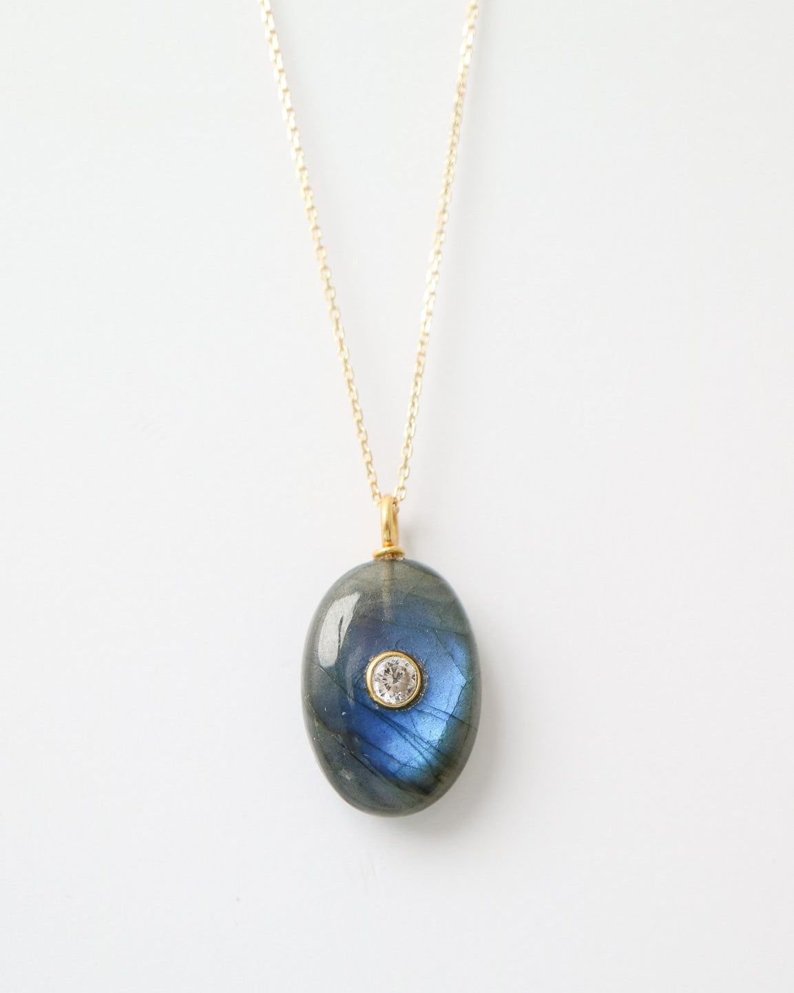 Eclipse Labradorite Pendant featuring a polished oval labradorite gemstone with natural blue flashes, a bezel-set cubic zirconia, and a gold plated sterling silver bail on a white background.