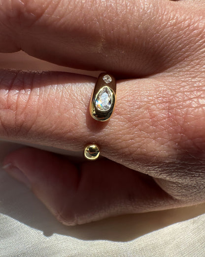 Gold ring with a diamond on a finger against a neutral background