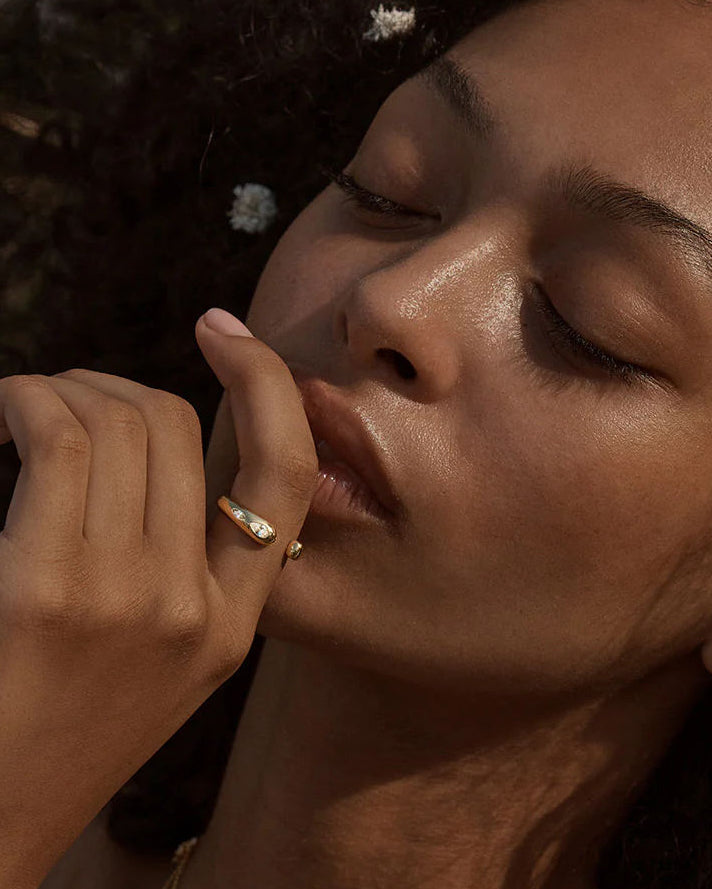 Close-up of a polished gold-plated statement ring with organic curves and two marquise-cut moissanite stones