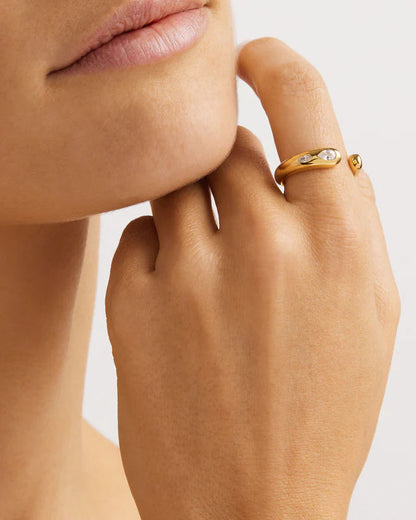 Close-up of a hand with a gold ring on a neutral background