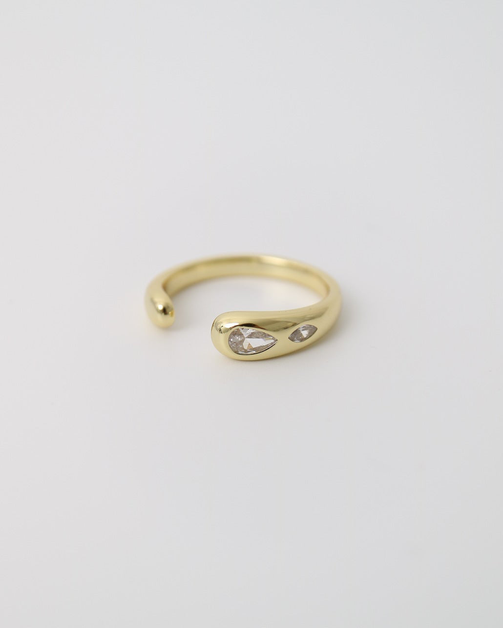 Close-up of a polished gold-plated statement ring with organic curves and two marquise-cut moissanite stones