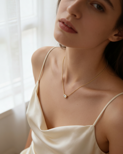 Woman wearing a delicate necklace with a small pendant in a softly lit room.